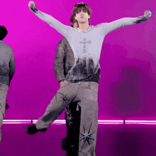 a man in a tie dye shirt with a cross on it is dancing on a purple background .