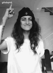 a woman wearing a beanie and a white shirt is giving the middle finger with gifsdayrol written below her