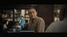 a man in a plaid shirt stands in front of a counter
