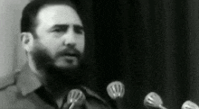 a man with a beard is giving a speech in front of a microphone .