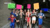 a group of people dressed in superhero costumes are walking down a street with a sign that says en directo