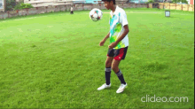 a boy is juggling a soccer ball on a field with clideo.com written in the corner