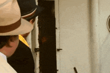 a man in a hat is looking out of a door