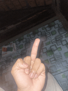 a person 's hand is giving the middle finger in front of a tiled floor
