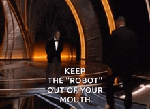 a man in a tuxedo stands on a stage with the words " keep the robot out of your mouth " written below him