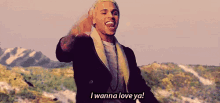 a man is standing in front of a mountain and says `` i wanna love ya ! ''