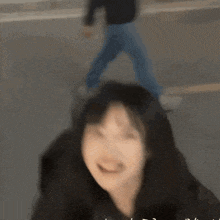 a blurry picture of a woman smiling with a person walking in the background .
