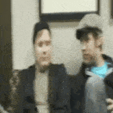 a blurry picture of two men sitting on a couch with one wearing a hat