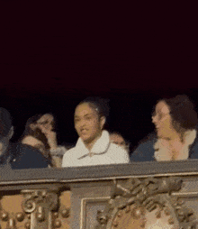 a group of people are sitting on a balcony at night