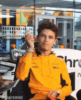 a man wearing an orange dell hoodie holds a green flag