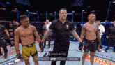 a referee stands between two fighters in a boxing ring