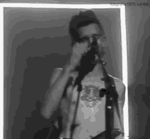 a man with a tattoo on his chest is singing into a microphone .