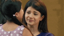 a woman is hugging a little girl who is crying and looking at her .