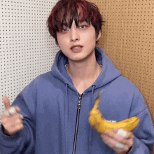 a man in a blue hoodie holds a banana