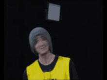 a man wearing a gray beanie and a yellow shirt is dancing with his arms in the air .
