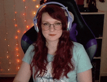 a woman with red hair wearing glasses and headphones is sitting in a chair .