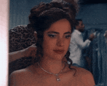 a woman wearing a tiara and a necklace is getting her hair done .