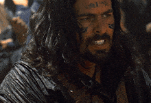 a man with long hair and a beard has a tattoo on his face that says ii