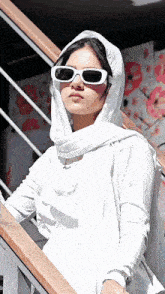 a woman wearing sunglasses and a white scarf