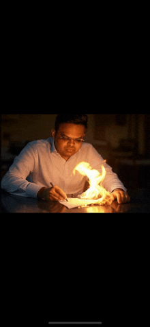 a man is writing on a piece of paper with flames coming out of his hand