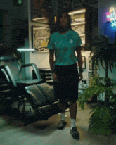 a man wearing a nike shirt and shorts stands in a dark room