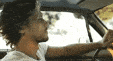 a man with long hair is driving a car .