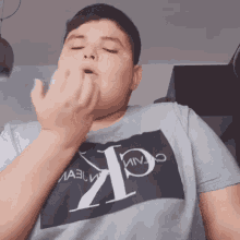 a man wearing a calvin klein t-shirt blows his nose