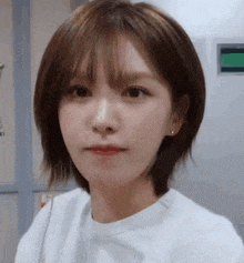 a close up of a woman with short hair wearing a white shirt .