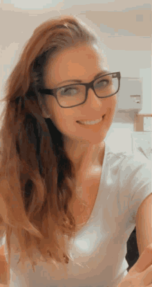 a woman wearing glasses and a white shirt is smiling