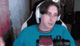 a man wearing headphones and a blue shirt is sitting in front of a microphone .