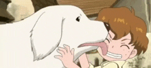 a boy is licking a dog 's nose with his tongue