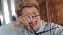 a woman wipes her nose with her glasses