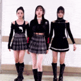 three girls are standing next to each other wearing plaid skirts and black tops