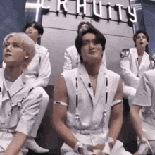 a group of men in white clothes are sitting on the floor .
