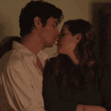 a man is kissing a woman on the forehead in a dark room