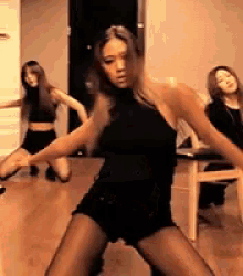 a woman in a black top and shorts is dancing in a room with other women