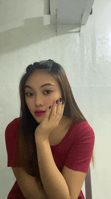 a woman in a red shirt with black nails is looking at the camera