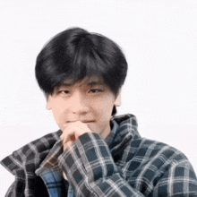 a young man wearing a plaid shirt is making a face