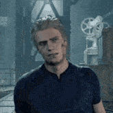 a man in a blue shirt is standing in front of a machine