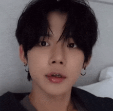 a close up of a young man wearing hoop earrings and a black shirt .