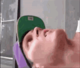 a man wearing a green hat and a purple shirt is laying down .