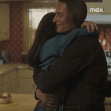 a man and woman hugging in a kitchen with a max logo in the background