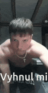 a man without a shirt is doing push ups with a cross necklace around his neck .