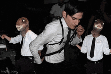 a man in a suit and tie is dancing with a lizard mask on his head