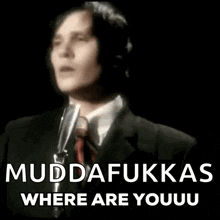 a man in a suit and tie is singing into a microphone while wearing a tie .