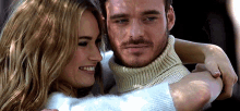 a man and a woman are hugging each other and the woman is smiling .