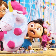 a little girl is holding a stuffed unicorn while standing next to a unicorn .