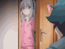 a girl in a pink pajama is standing in a doorway looking at a boy .
