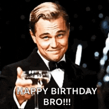 a man in a tuxedo is holding a glass of champagne and saying `` happy birthday bro ! ''