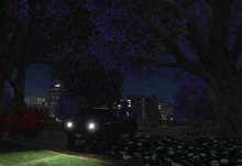 a car is parked under a tree at night with purple flowers
